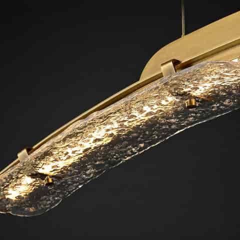 Close up of copper linear chandelier with thick rippled clear glass showing layered refraction and warm illuminated texture