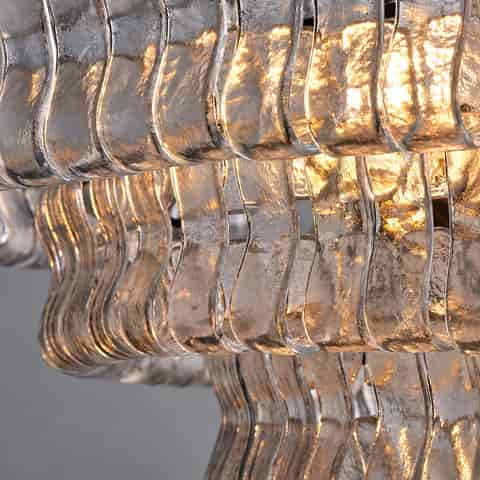 Close up of textured clear glass chandelier panels showing rippled surfaces and warm light reflections