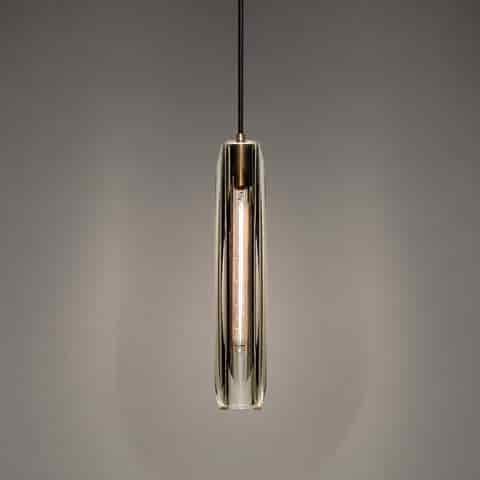 Slim clear crystal pendant light with warm copper frame and elongated sculptural design