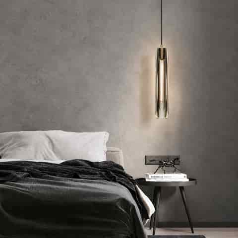 Clear crystal bedside pendant light with copper accents in a modern bedroom