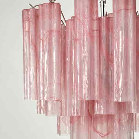 Close up of pink textured chandelier tubes with scalloped edges and warm light creating layered shadows