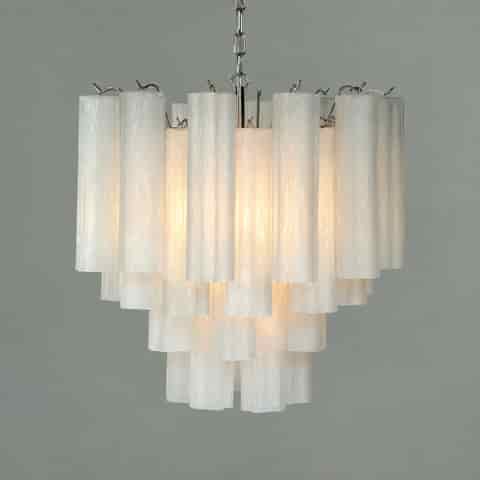 White textured chandelier with layered tubular shades, translucent surfaces, and warm illumination against a neutral background