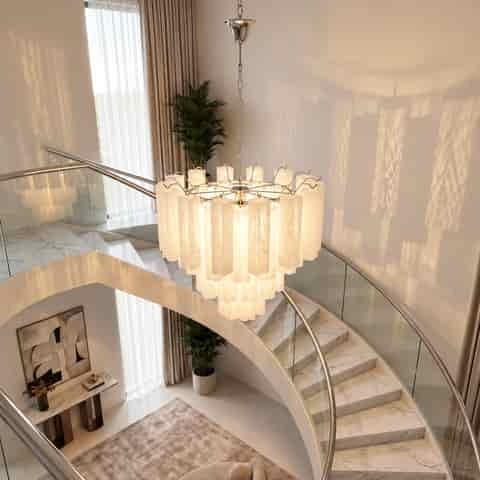 Tiered cream glass chandelier suspended above a curved staircase in a contemporary luxury home