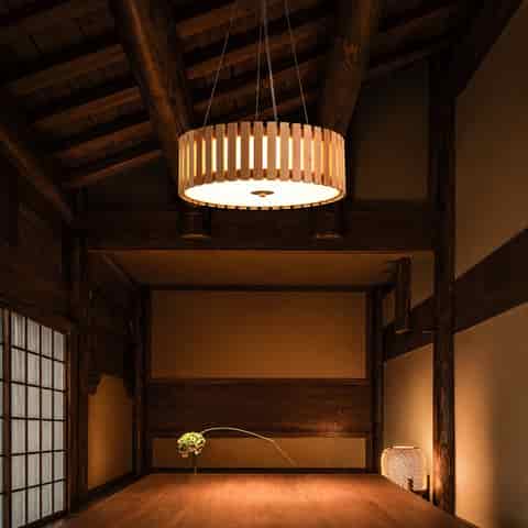 Natural wood slat drum pendant chandelier with warm diffused light in a Japanese style dining room