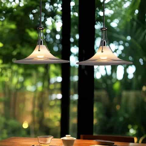 Pair of modern frosted glass saucer pendant lights with polished metal frames suspended above a wood dining table