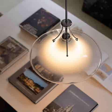 Top view of frosted glass saucer pendant with clear glass edge, polished metal accents and warm diffused illumination