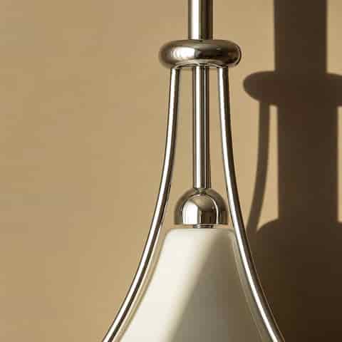 Close up of polished metal suspension frame and frosted glass shade on a modern saucer pendant light