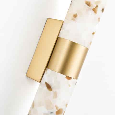 Close up of natural brass frame and terrazzo diffuser on LED wall sconce