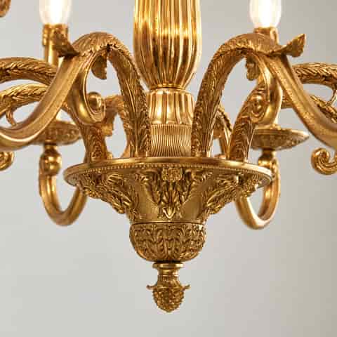 Close up of ornate gold chandelier craftsmanship with acanthus style leaves, scrollwork and a richly detailed central bowl