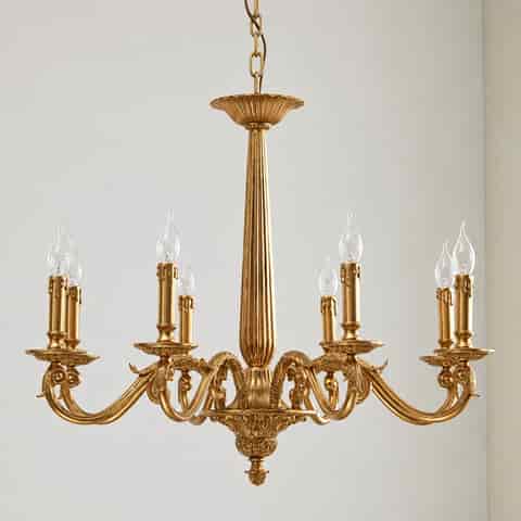 Traditional gold chandelier with symmetrical scrolling arms, decorative leaf motifs and candle style lights