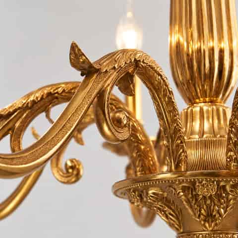 Luxury gold chandelier detail featuring a fluted central column and sculptural candle style light