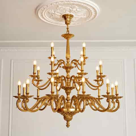 Gold chandelier mounted beneath an ornate decorative ceiling medallion in a classic interior