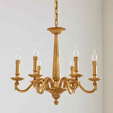 Elegant gold chandelier with ornate curved arms, candle style lights and a sculpted central column