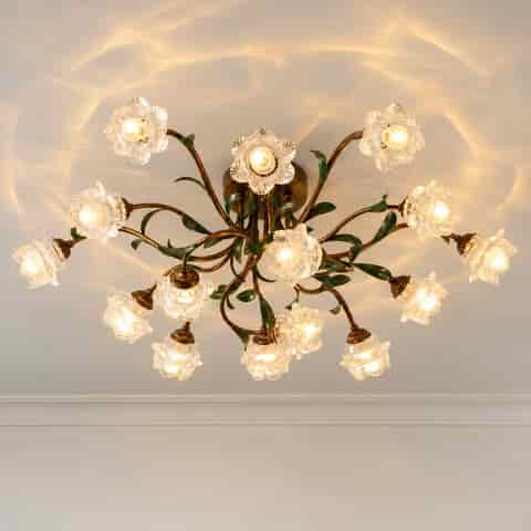 Low angle view of a vintage botanical ceiling light with sculpted metal leaves and textured glass flower shades