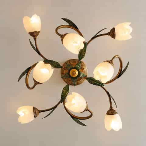 Top view of a botanical floral ceiling light with curved arms, green leaves, and multiple flower shaped shades