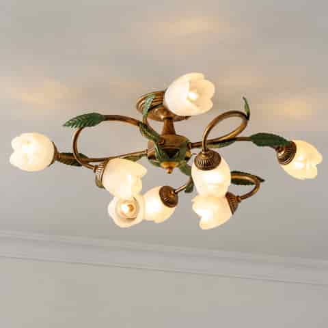 Side view of a vintage floral ceiling light with white flower shades, curved branches, and green leaf accents
