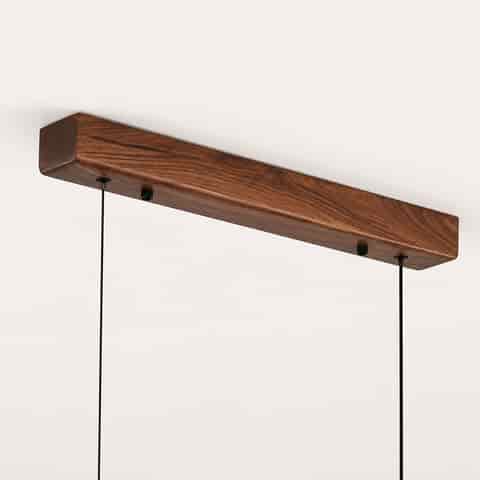 Close up of walnut wood ceiling canopy and black suspension cables for a linear pendant light