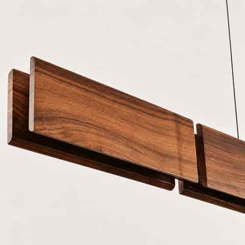 Close up of layered walnut wood panels with natural grain and rounded edges on a linear pendant light