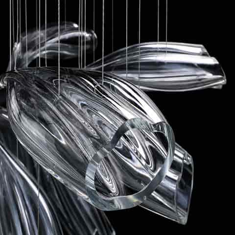 Close up of thick clear sculpted chandelier petal with flowing texture, polished edge and suspension cables.