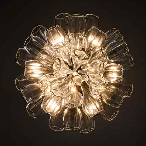 Bottom view of illuminated sculptural flower chandelier with layered clear petals and glowing