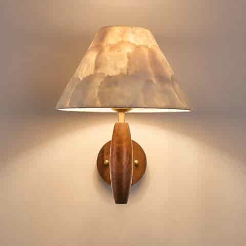 Close up of tapered natural Capiz shell shade on a warm wood wall sconce