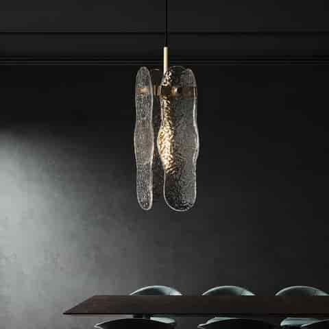 Sculptural textured glass pendant light with brass finish frame above a modern dining table