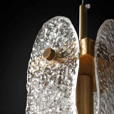 Modern brass finish pendant light with sculptural clear hammered glass panels on black background