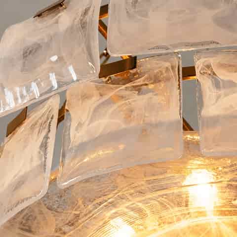 Close up of a gold metal and textured glass chandelier with translucent sculptural glass panels