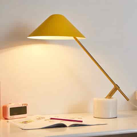 Mustard yellow cantilever table lamp with a white stone base and polished gold angled arm