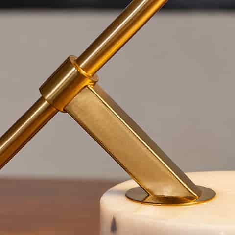 Close up of the polished gold metal joint and angled support structure on a stone base table lamp
