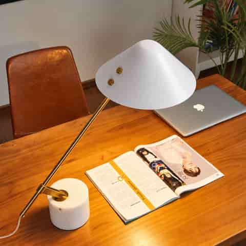 Sculptural white stone and polished gold cantilever table lamp styled on a modern wooden desk