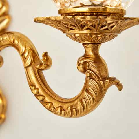 Antique gold wall sconce detail with ornate scrollwork, carved leaf motifs and decorative metal arm