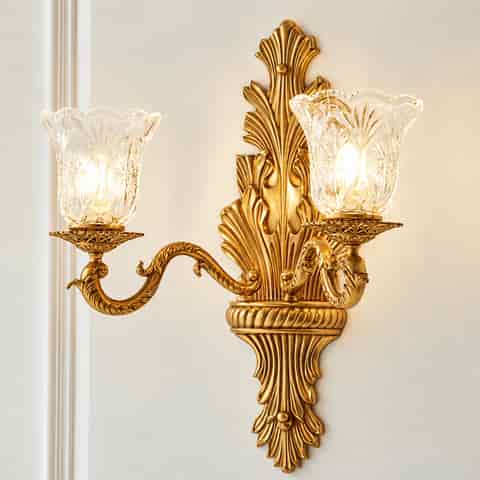 Close up of ornate antique gold wall sconce frame with carved floral details and clear patterned glass shade