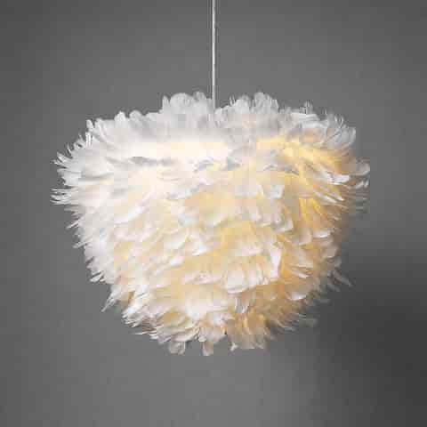 White feather pendant light with layered fluffy shade and warm ambient glow against a gray wall